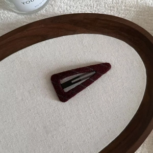 Detailed texture of burgundy wool felt triangle hair clip in a wooden tray display
