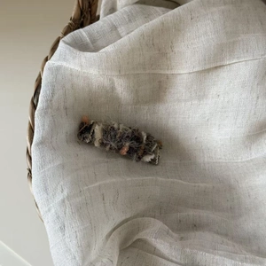 Close-up of plush textured knit hair clip with grey and orange mohair wool fibers