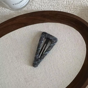 Detail of dark grey tweed wool texture on triangle BB hair clip with black metal base