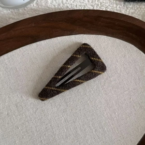 Close-up of a brown striped knit fabric hair clip on a wooden and linen background