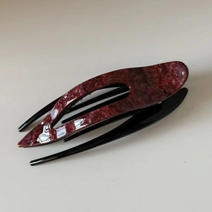 Detailed top view of large acetate hair clip with red marble texture and black finish