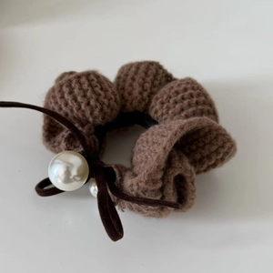 Brown knitted scrunchie with white pearls and silk bow on a white background