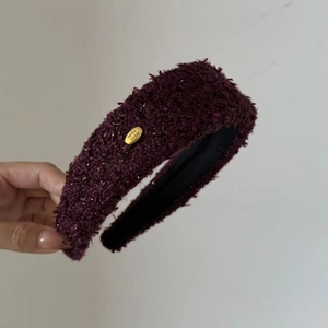 Detail of burgundy tweed headband with gold metal plate and handcrafted texture