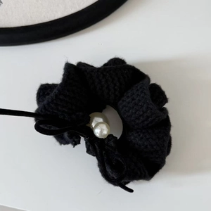 Close-up of black knitted hair scrunchie with velvet bow and white pearls detail