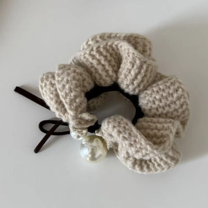 Detailed close-up of knitted scrunchie with elegant faux pearl charms and woven texture