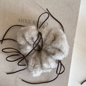 Détail du chouchou en peluche gris clair avec lien décoratif en cuir marron vintage
