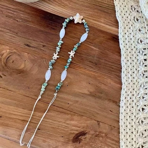 Detail of bohemian turquoise stone beads with starfish and star charms on wood