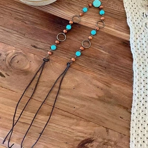 Detail view of Bohemian turquoise and wooden beads with bronze rings on wood background