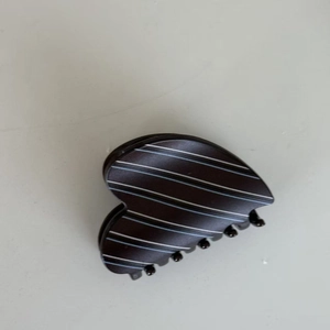 Macro shot of striped heart-shaped hair claw clip with blue and white pattern