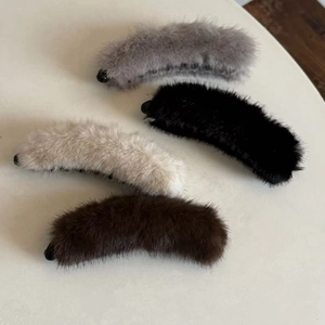 Detailed view of four fluffy faux mink fur banana hair clips in neutral colors