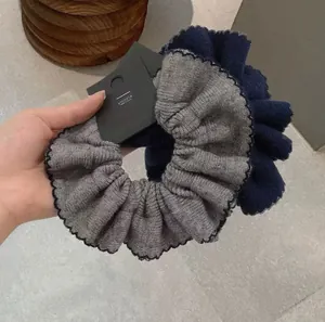 Detailed view of grey and dark blue knitted scrunchies with elegant black scalloped edges