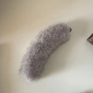 Detail view of a gray plush faux fur banana hair clip with secure black plastic fastener