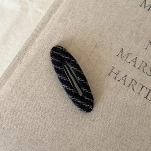 Close-up of vintage striped knit hair clip on a textured book for elegant styling