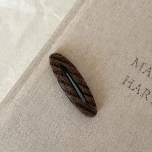 Close-up of vintage brown striped plush hair clip on a minimalist linen background