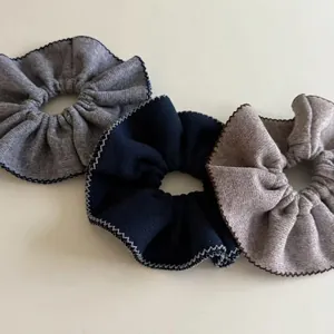 Three knitted rib scrunchies in grey, navy, and coffee with wavy contrast edge stitching
