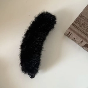 Detail of plush black mink fur banana hair clip on a vintage book background