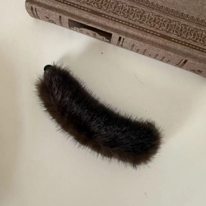 Detail of dark brown faux mink fur banana hair clip on a minimalist vintage background