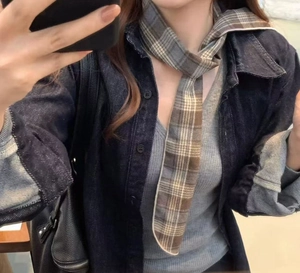 Close-up of vintage plaid scarf necklace in brown and cream styled with denim jacket