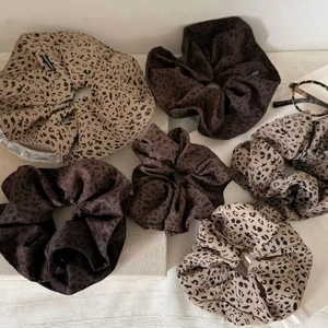 Fashionable leopard print satin scrunchies in various shades on a minimalist fabric