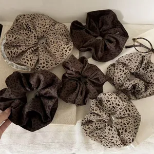 Close-up of leopard print satin scrunchies in beige and coffee colors with soft silk texture