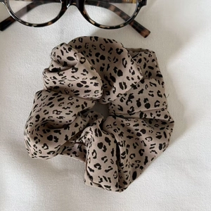 Detailed macro shot of satin leopard print hair scrunchie with fashionable eyewear accents