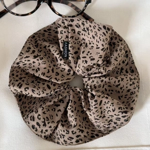 Detailed close-up of leopard print satin hair scrunchie with fashion label on white fabric