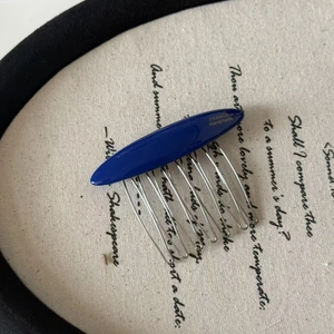 Detail of a handmade hair comb with blue resin oval inlay and silver metal teeth