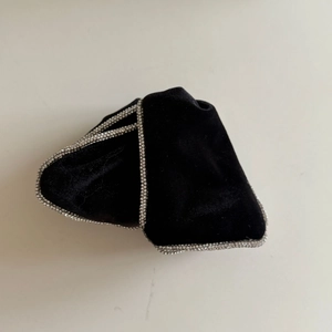 Dettaglio della pinza per capelli in velluto nero con bordi di strass argento lucidi
