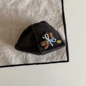 Detailed macro view of a brown plush bear hair clip with a gold SMILE metal emblem tag