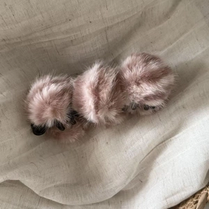 Détail de la pince à cheveux banane en peluche douce rose poudré sur fond de tissu