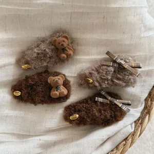 Detail of plush brown bear and plaid bow hair clips with gold handmade metal tags