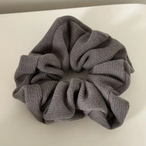 Close-up of grey wool knit scrunchie with waffle texture and elastic fabric detail