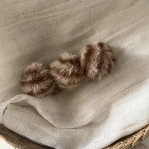 Gros plan de trois boules en peluche marron automne sur un fond en lin texturé