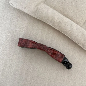 Elegant tortoiseshell banana hair clip in red-brown marble pattern on beige background