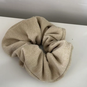 Detailed macro shot of beige ribbed knit scrunchie texture with soft fabric folds