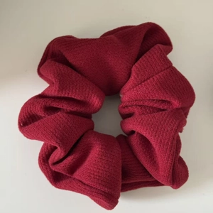 Detailed view of the dark red ribbed knit texture and soft pleats of the hair scrunchie