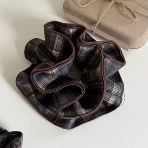 Macro shot of a plaid scrunchie with dark brown edges and vintage gift box background