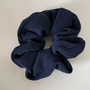 Detailed view of dark blue textured knitted wool scrunchie with elastic hair tie band