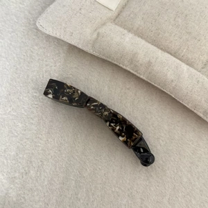 Macro detail of tortoiseshell acetate banana hair clip showing marble texture and hinge