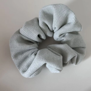 Light blue knit scrunchie with vertical ribbed texture and soft pleated fabric design