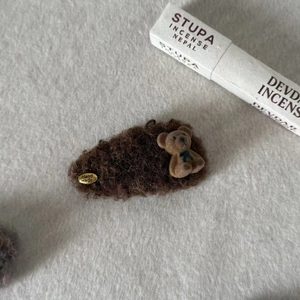 Close-up of fluffy brown plush hair clip with handmade tag and cute teddy bear detail