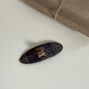 Detailed close-up of navy plaid fabric hair clip featuring a cute 3D brown bear with gold bow