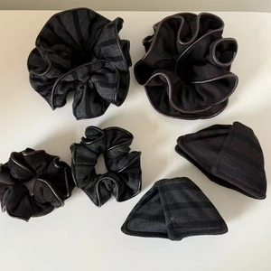 Detailed view of black striped scrunchies with faux leather trim and high-quality fabric texture