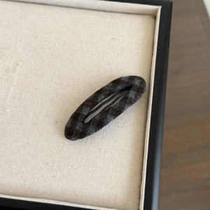Détail d'une pince à cheveux goutte d'eau en velours gris foncé et son clip en métal