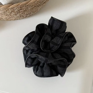 Close-up of striped knit scrunchie with black leather trim and soft texture