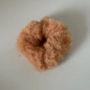 Gros plan d'un chouchou en peluche camel doux avec une texture duveteuse pour cheveux