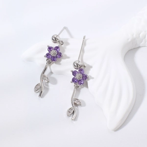 Dettaglio ravvicinato di orecchini a fiore viola con accenti di foglie e finitura argento