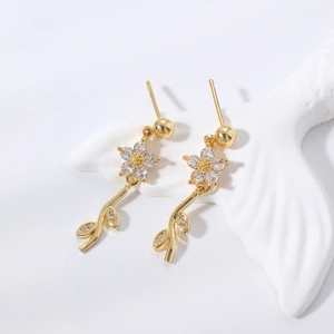Dettaglio di eleganti orecchini a fiore dorati con intarsi in zircone e delicati accenti di foglie