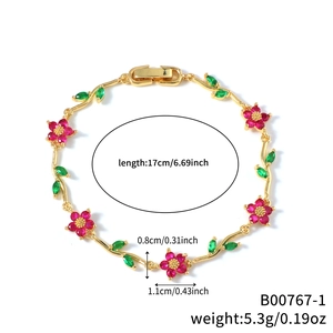 Elegante pulsera dorada con flores de circón rojo y hojas verdes en fondo blanco