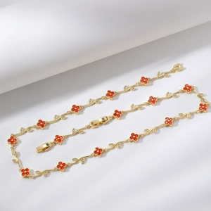 Elegante collana a tralcio dorato con quadrifogli rossi e scintillanti dettagli in cristallo